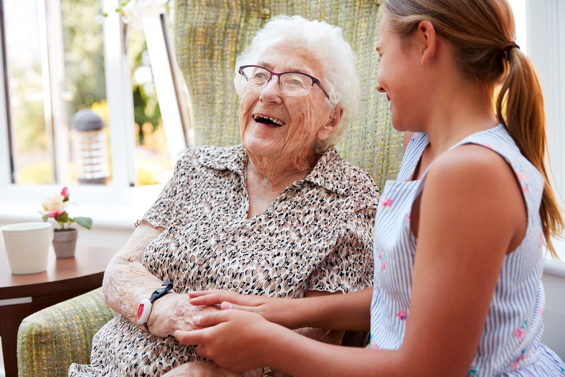 Grandmother and granddaughter smiling and holding hands indoors