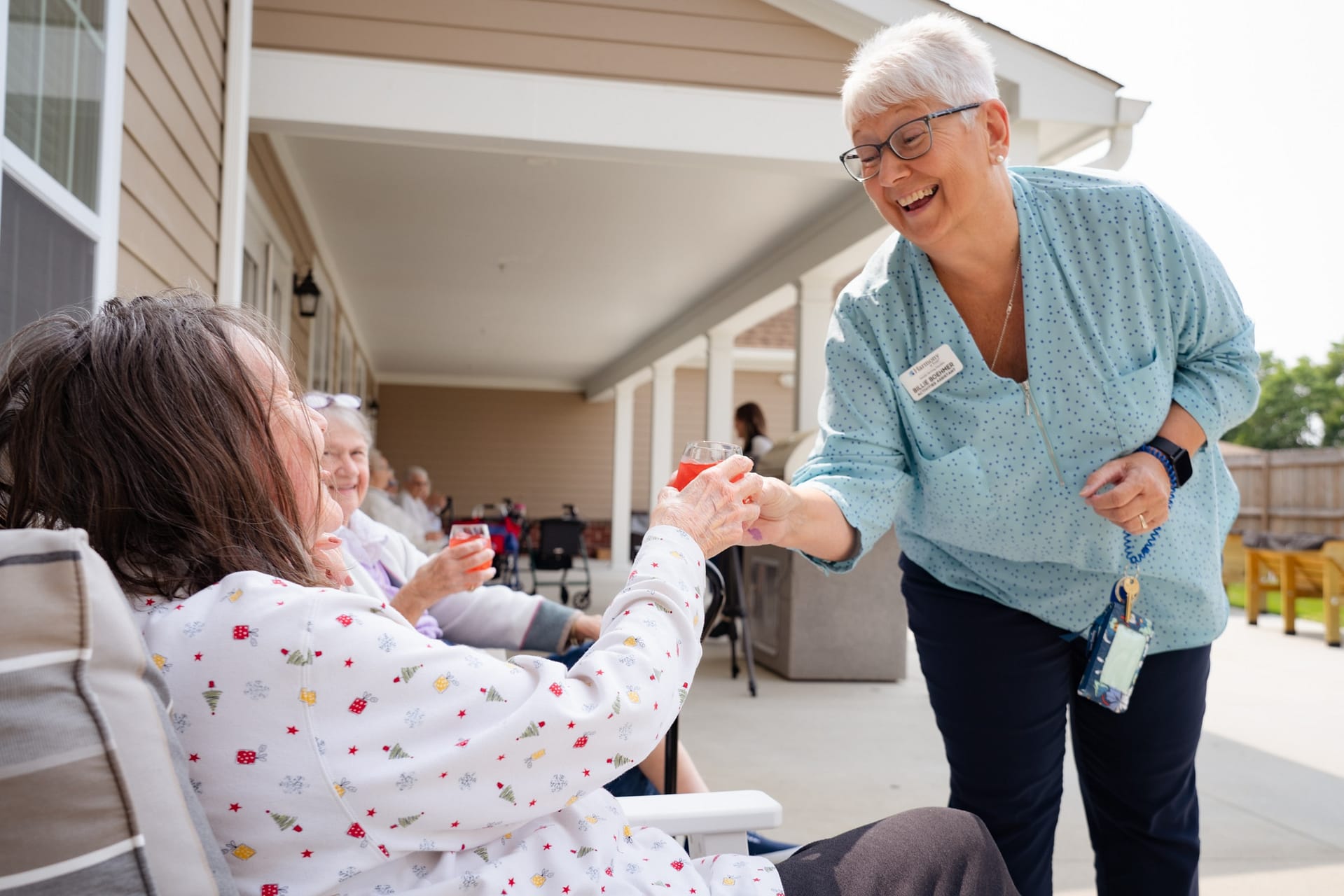 Caregiver serving drinks to seniors on porch