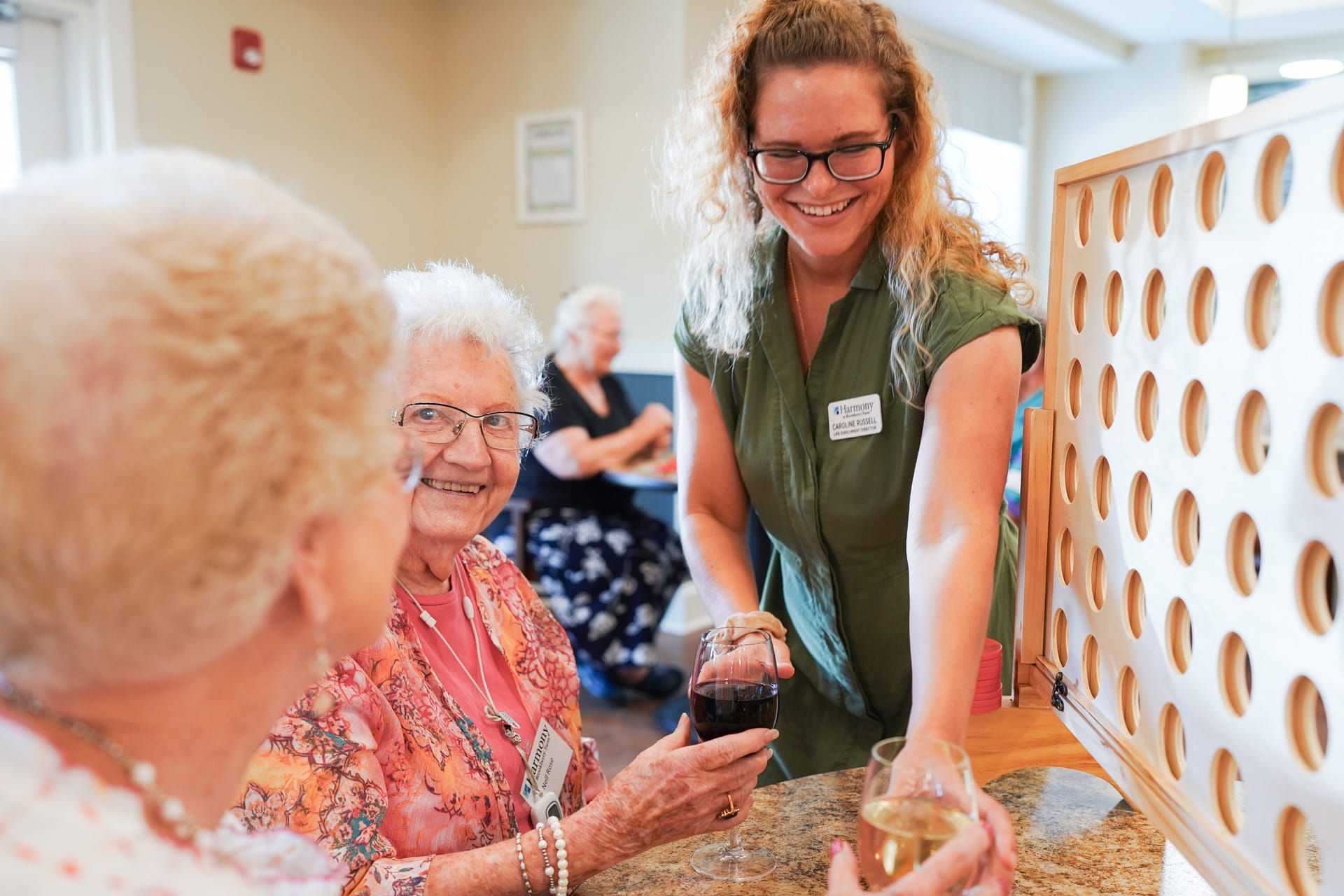 Caregiver and seniors playing Connect Four with wine