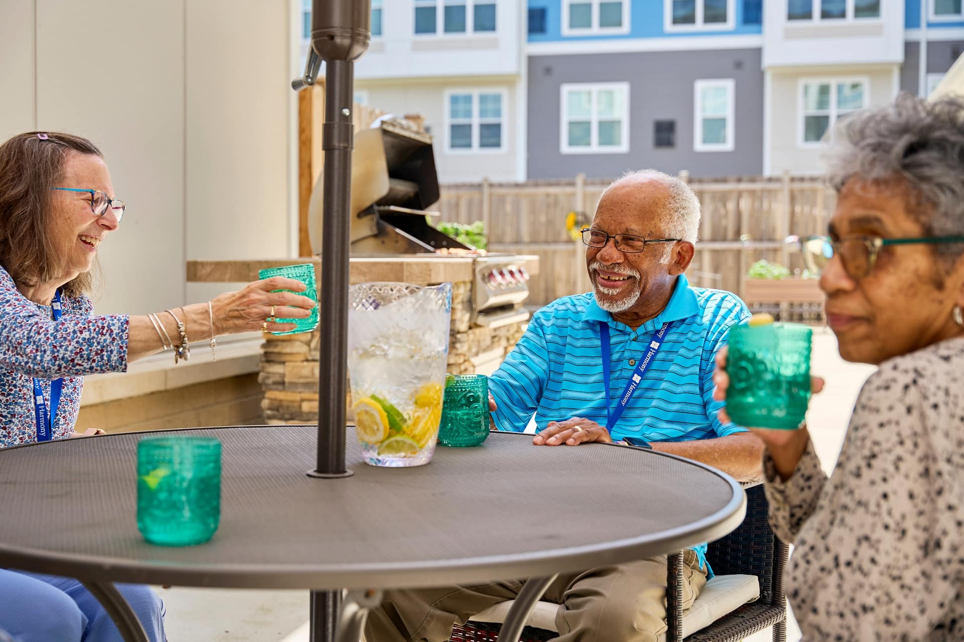 Three seniors laughing at outdoor patio table