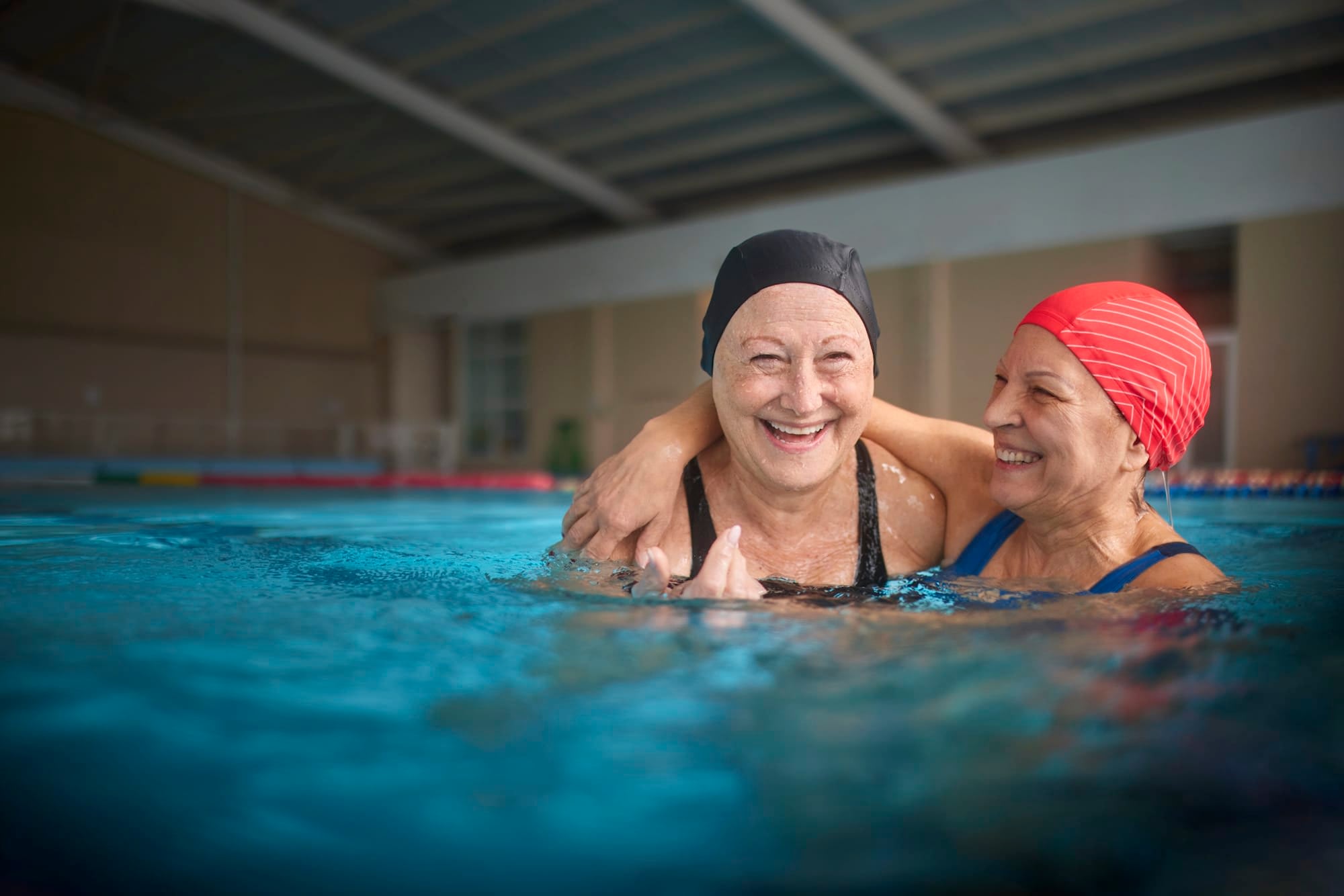 Two people smiling in an indoor pool.