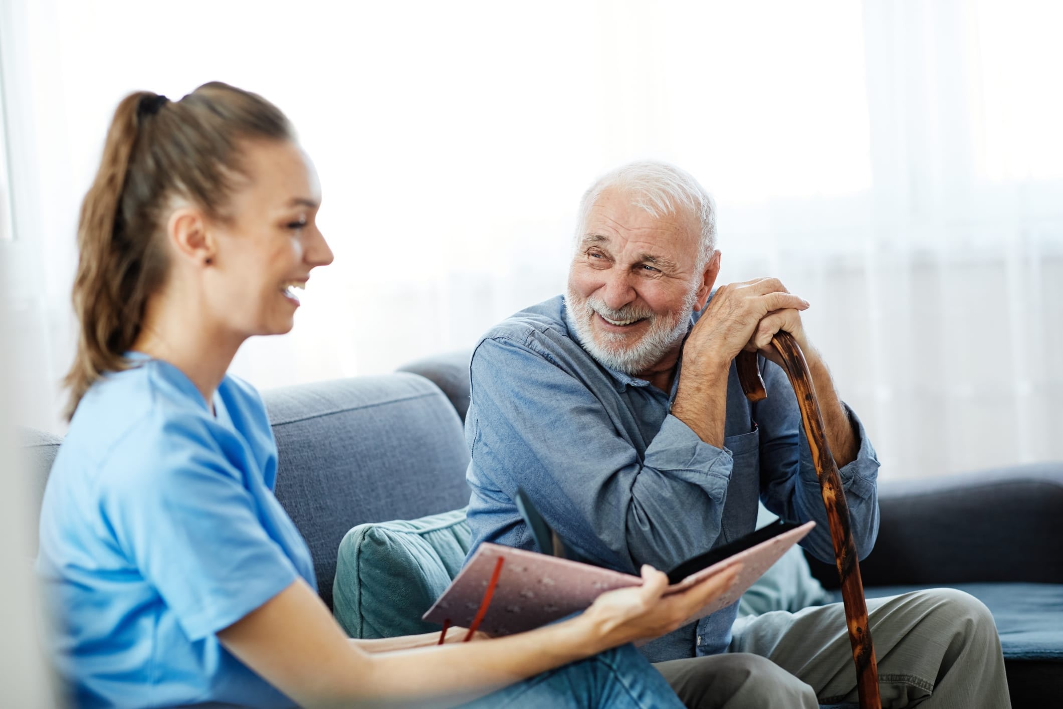 Senior man and young woman looking at a book and smiling at each other.