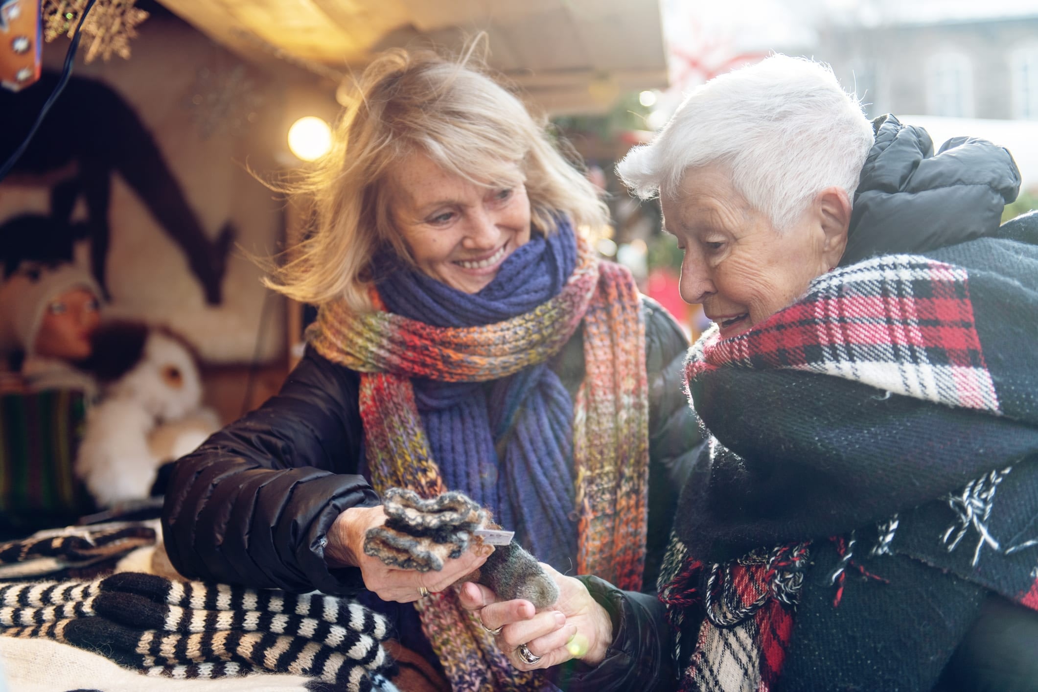 Senior woman and younger woman examining wool gloves at an outdoor bizarre.