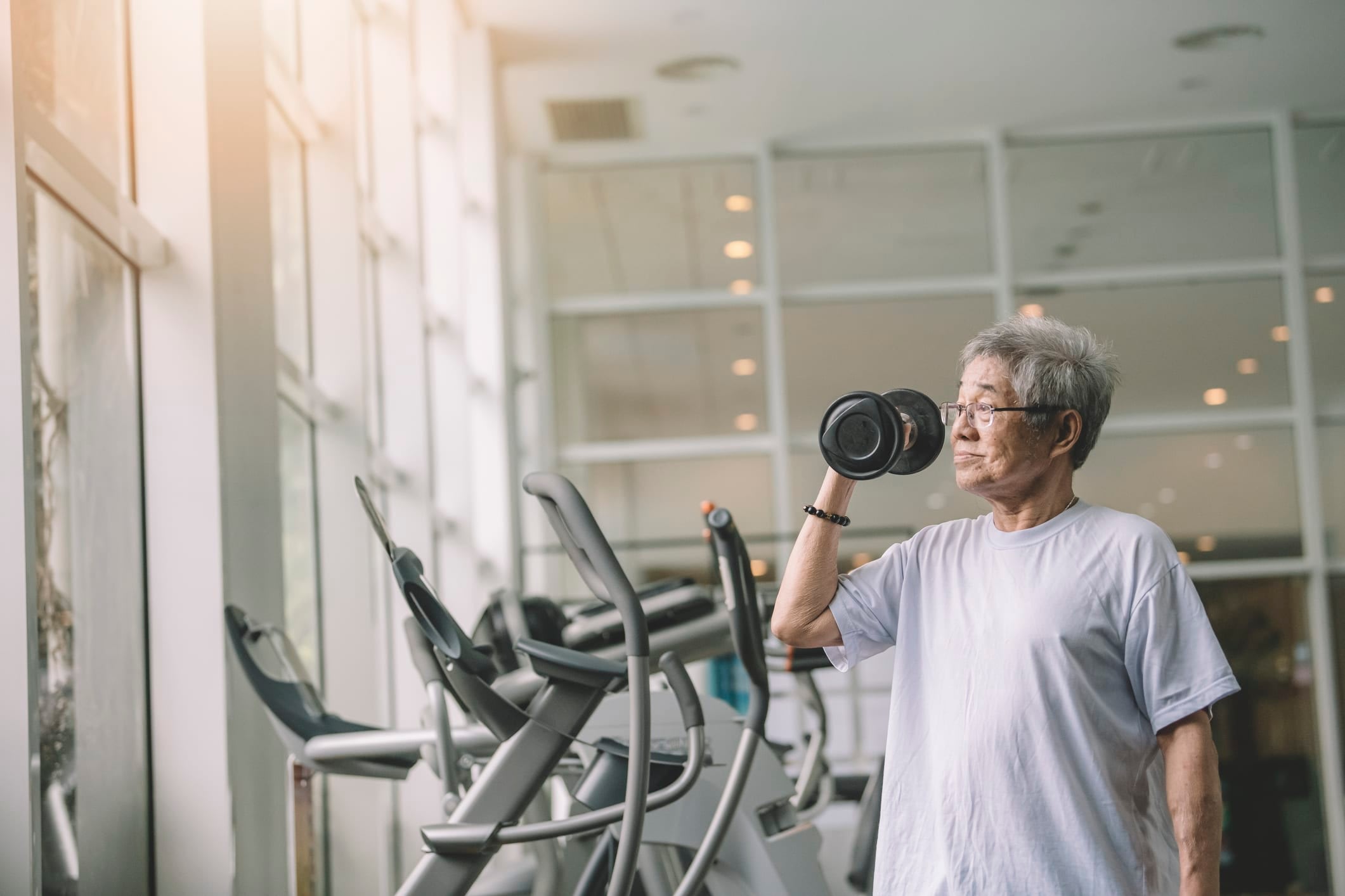 Senior man working out with dumbbell in a contemporary gym