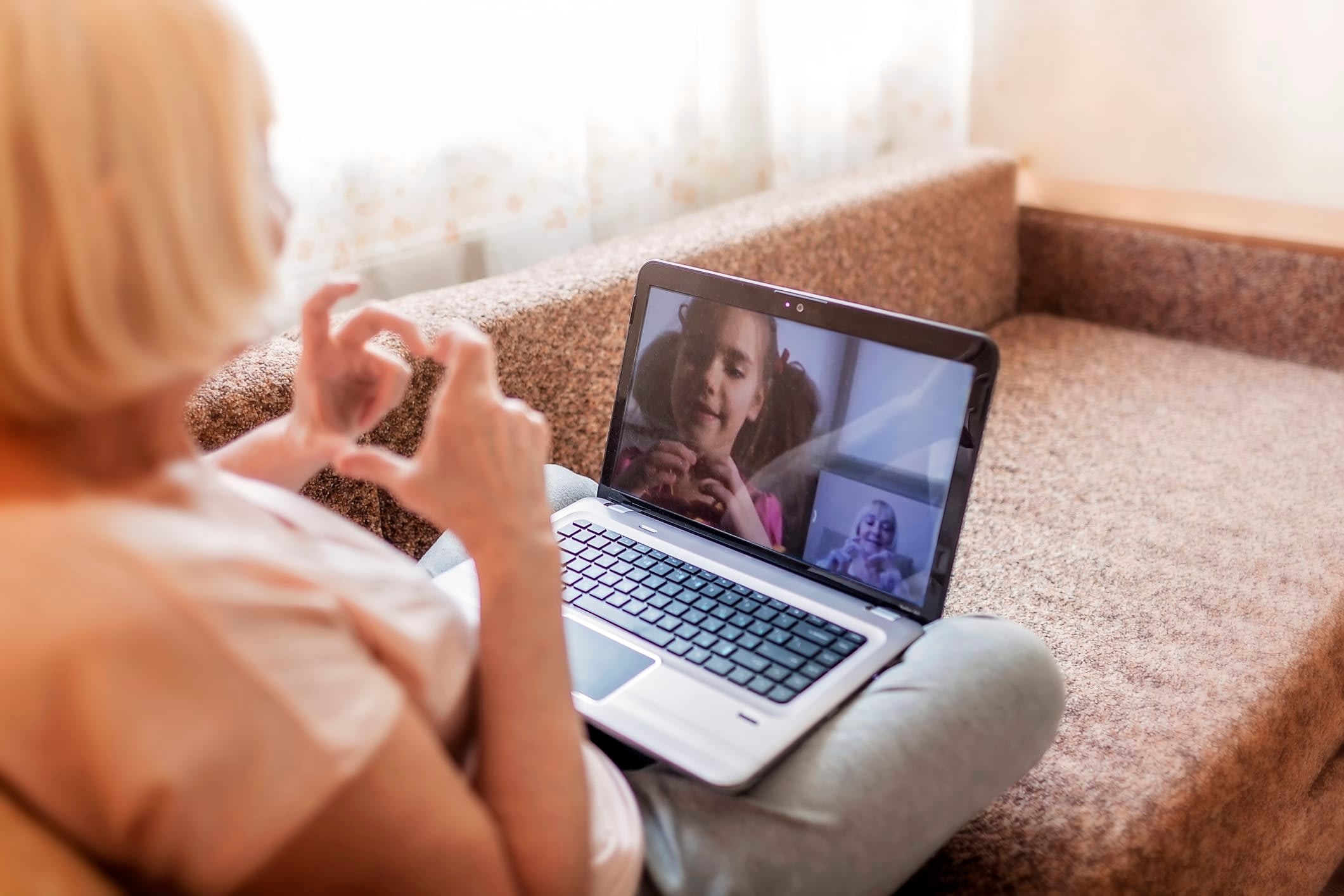 A senior-aged woman talks to a young girl on video chat.