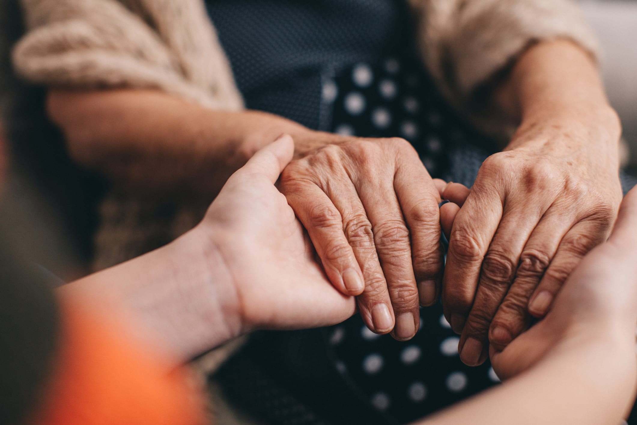 Woman comforting and holding the hands of a senior woman