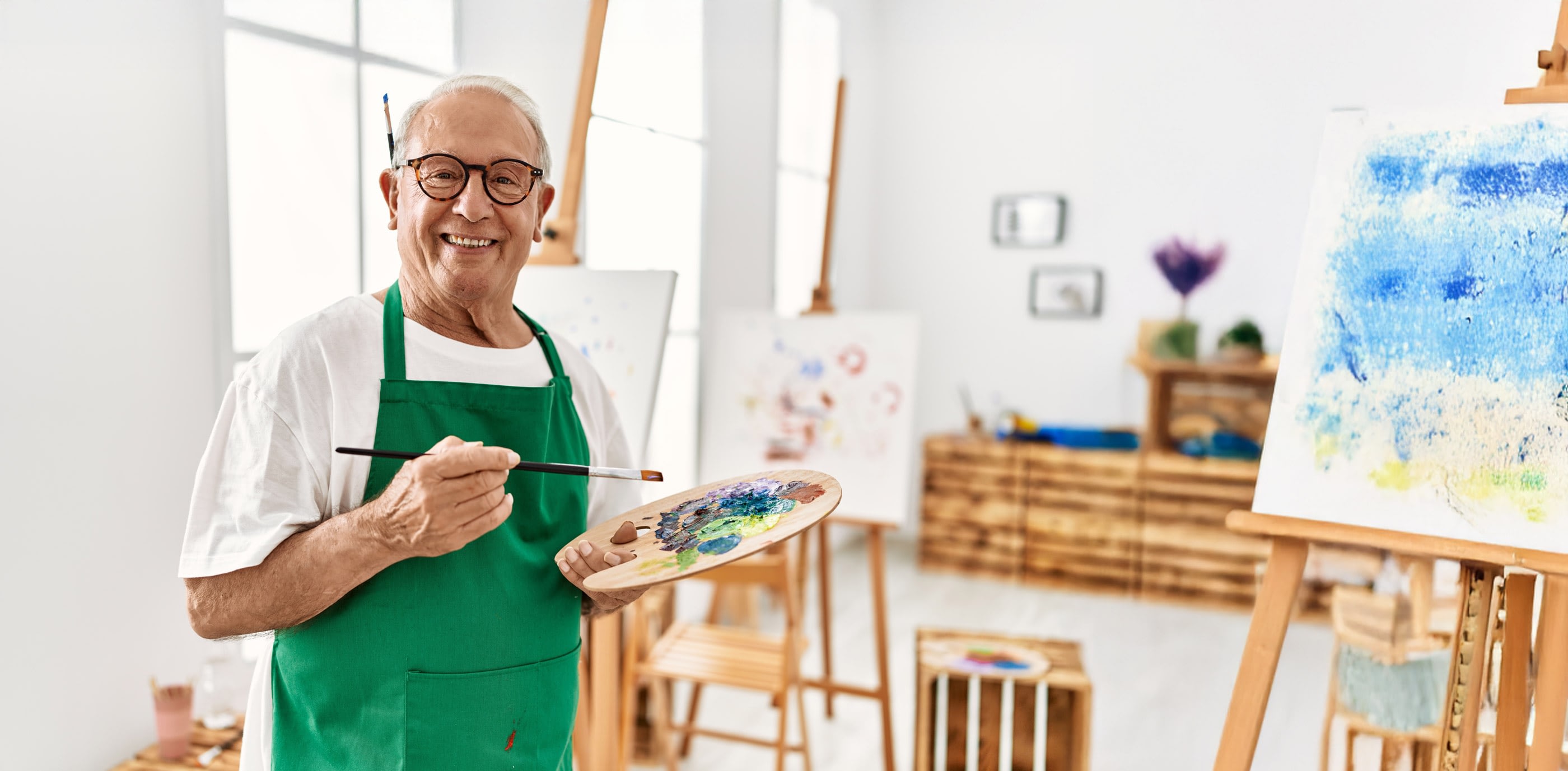 Senior man painting in bright art studio