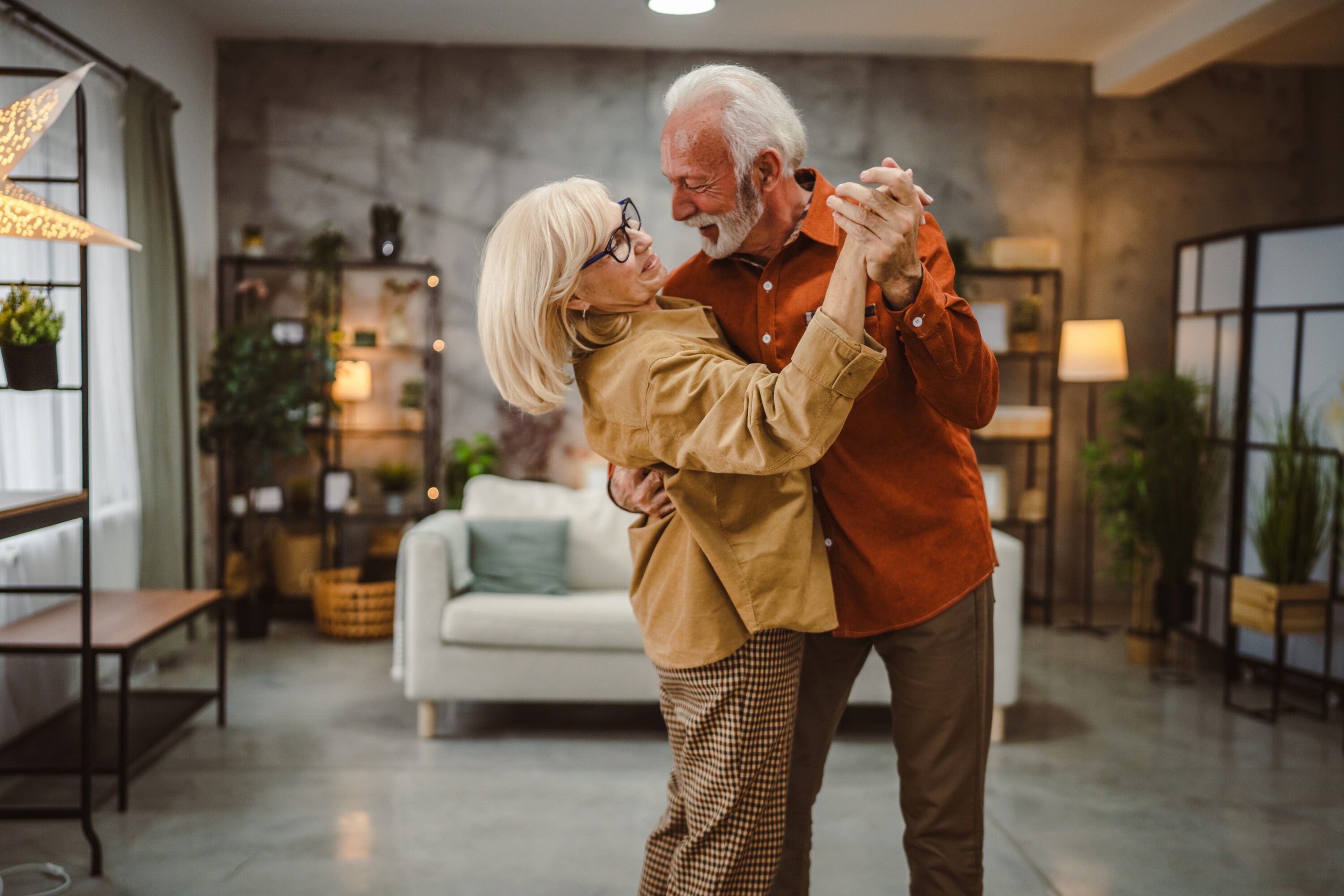 Elderly couple dancing in cozy living room