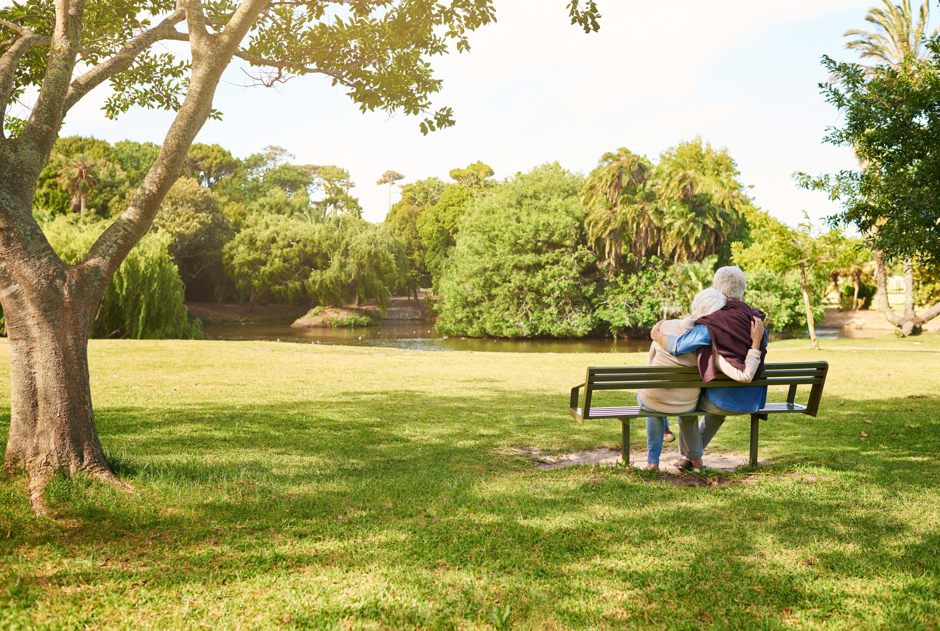 An elderly couple sitting on a bench at Brightwater Senior Living