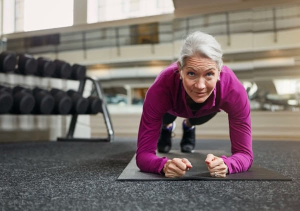 Older woman doing plank exercise in gym