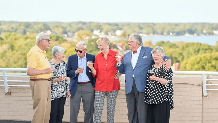 Six seniors toasting on scenic balcony