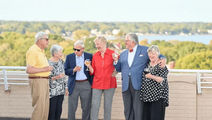 Six seniors toasting on scenic balcony
