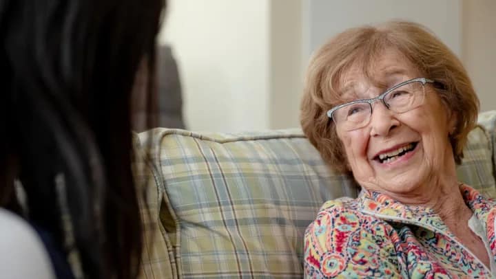 Smiling elderly woman talking on a couch